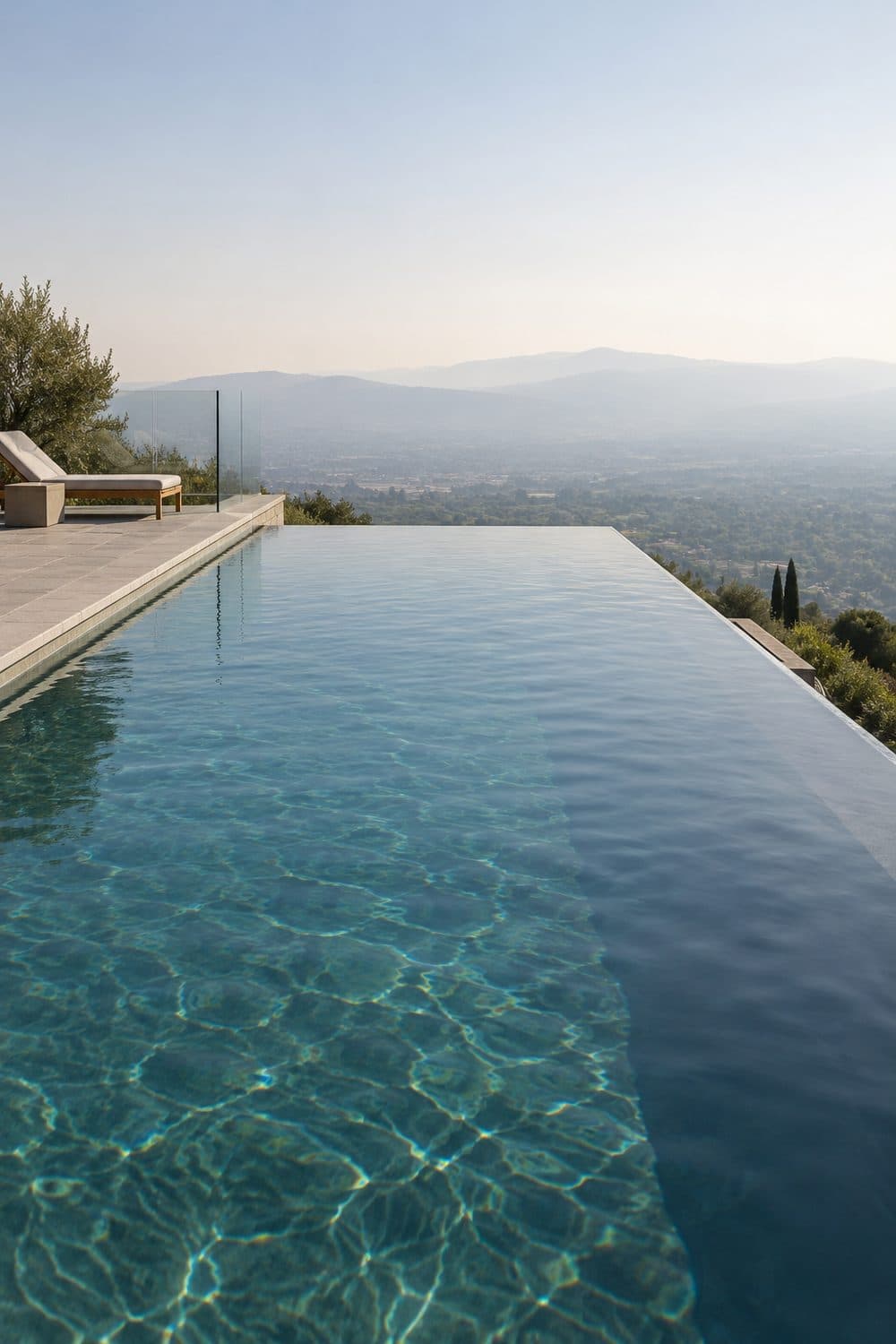 AI concept image: an infinity edge pool on a slope with the water meeting a hazy valley view at golden hour