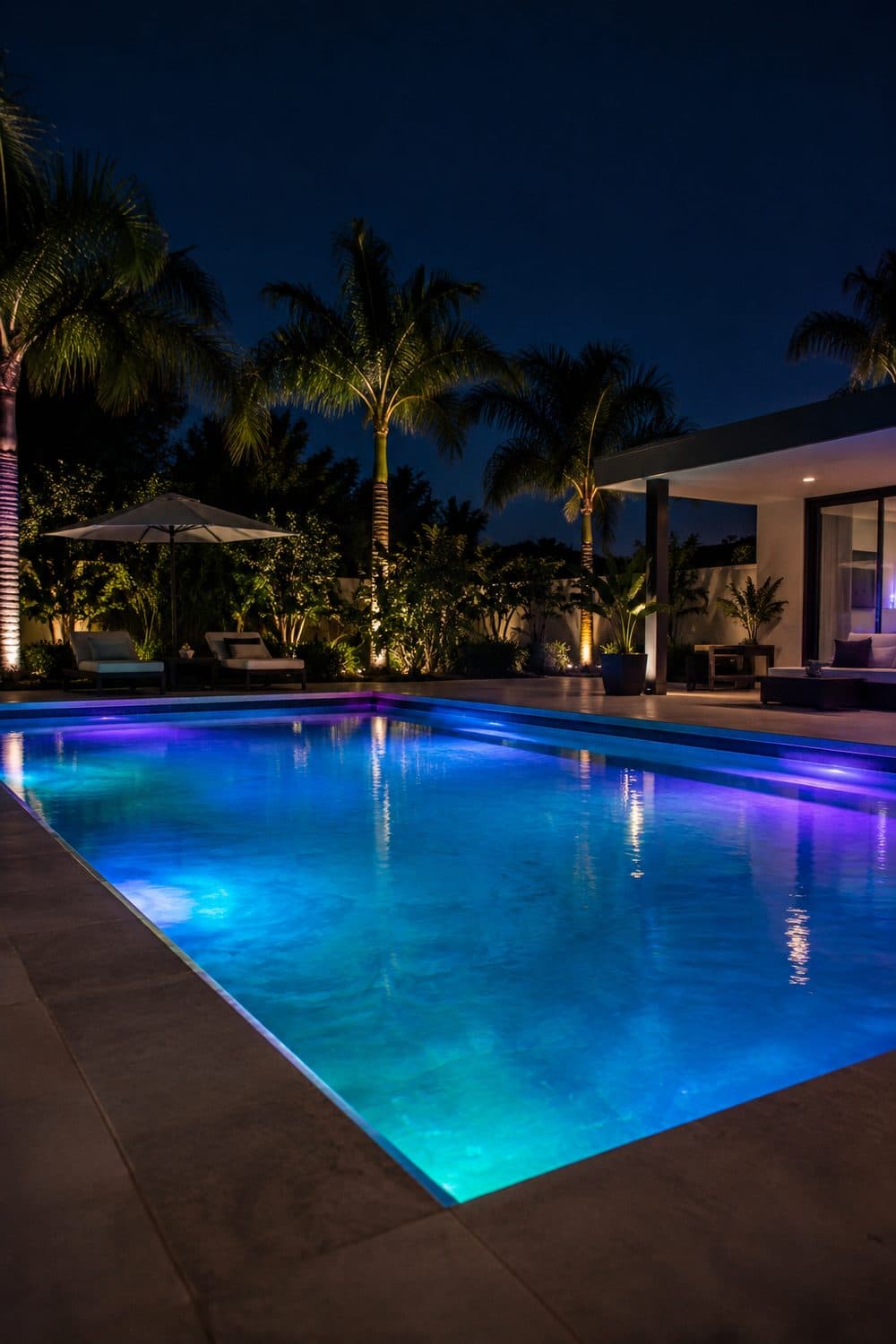 AI concept image: a pool lit in blue, teal and violet at night, palms lit from below