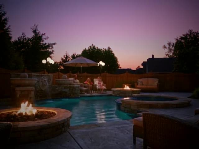 A father holds an infant in a lit spa at golden hour. A moment from the Build to night Story template.